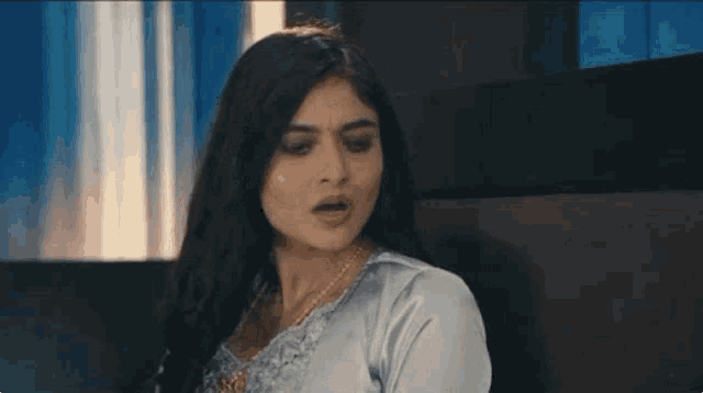 a woman with long hair is sitting in a chair with her mouth open .