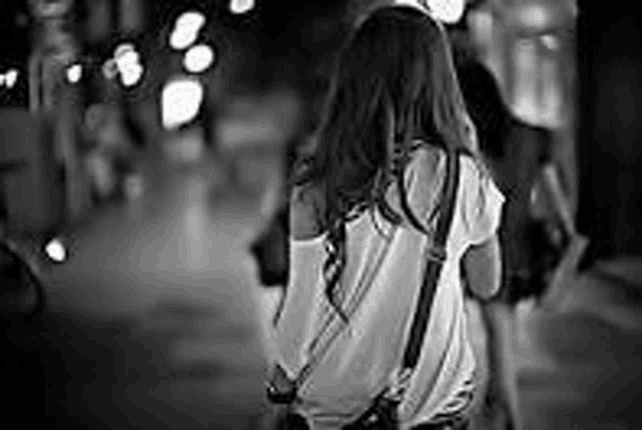 a black and white photo of a woman walking down a city street .