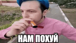 a man wearing a pink shirt and a blue hat is eating a snack .