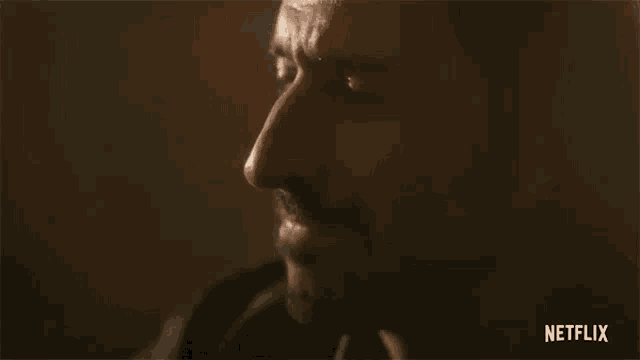 a close up of a man 's face in a dark room with a beard .