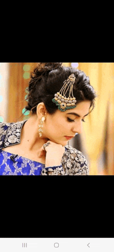 a woman wearing earrings and a headpiece is looking down
