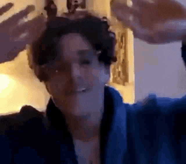 a man in a blue robe is making a funny face while holding his hands up in the air .