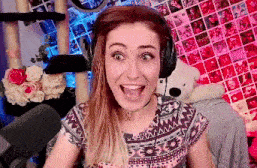 a woman wearing headphones and a choker smiles with her mouth wide open