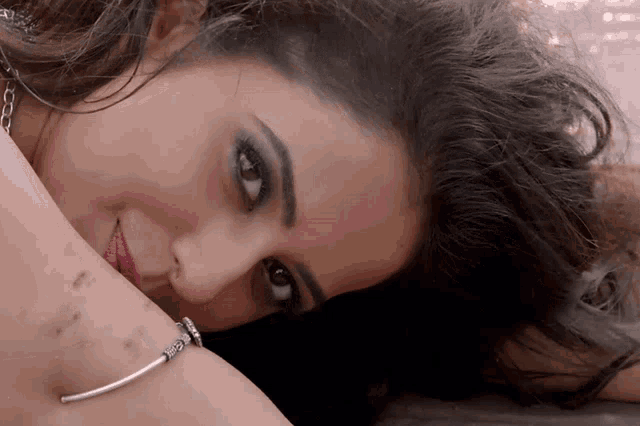 a close up of a woman 's face with a bracelet on her wrist that says ' i love you ' on it