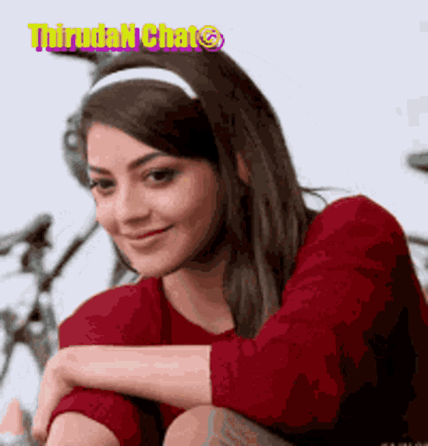 a woman wearing a red sweater and a white headband is sitting on the floor .