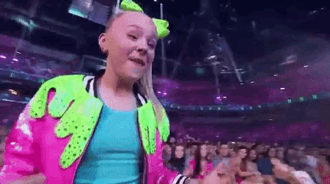 a girl is dancing in front of a crowd in a stadium .