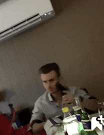 a man sits at a table with a bottle of water and a bottle of soda