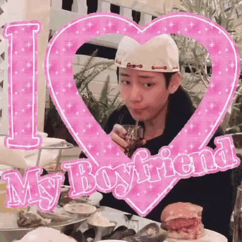 a man is sitting at a table drinking through a straw in front of a pink heart .