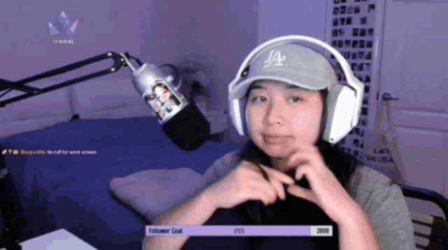 a girl wearing headphones and a la hat shows off her follower goal