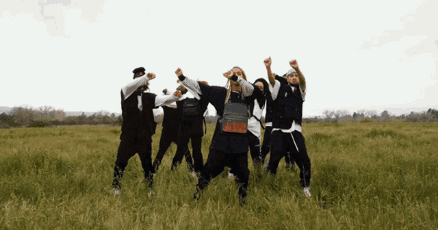 a group of people are dancing in a field and one of them is wearing a black shirt that says ' blood ' on it