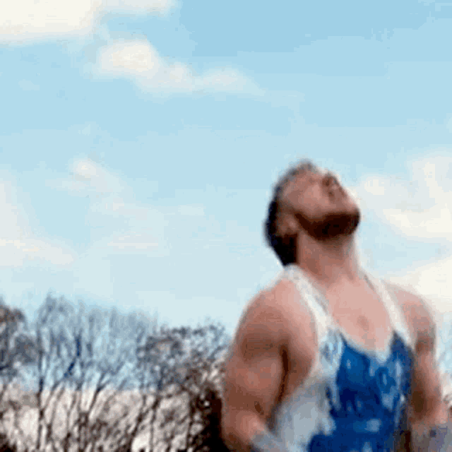 a man in a blue and white tank top is jumping in the air .