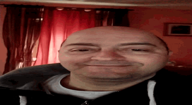 a man 's face is shown from above in front of a red curtain