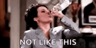 a woman in a suit is drinking water from a glass .