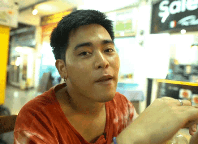 a man sitting in front of a sale sign