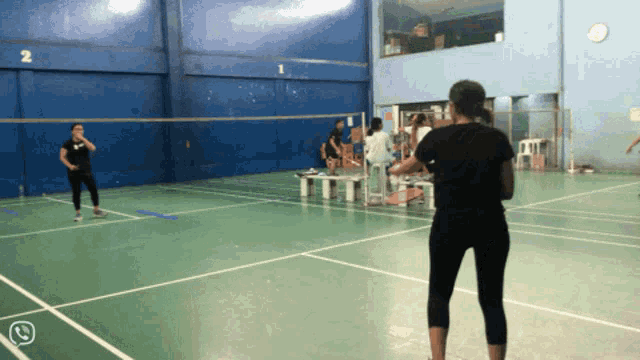 a group of people are playing badminton on a court with the number 2 on it