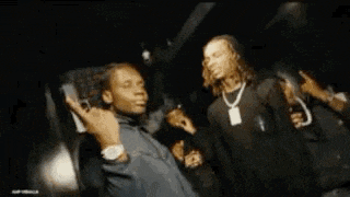 a man is holding a gun in his hand and another man is standing next to him .
