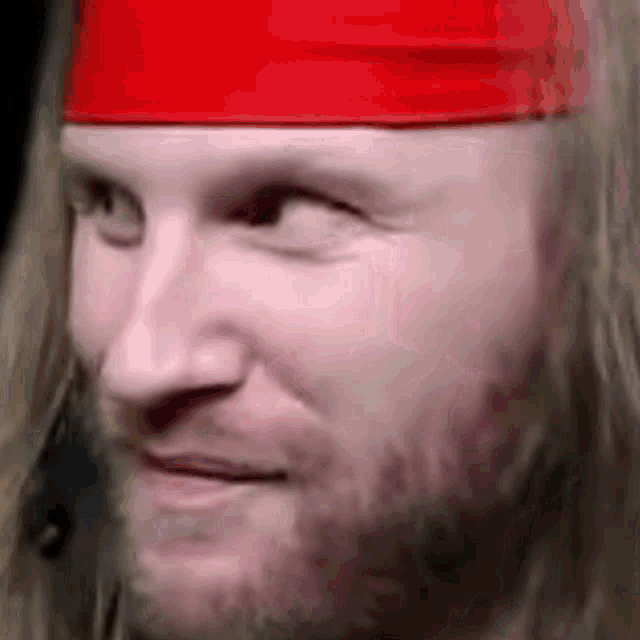 a man with long blonde hair and a beard wearing a red headband .