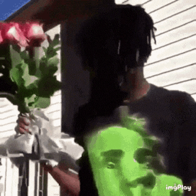 a man is holding a bouquet of red roses in front of a house .