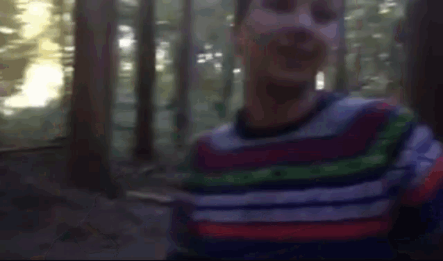 a blurry picture of a man in a striped shirt giving a thumbs up