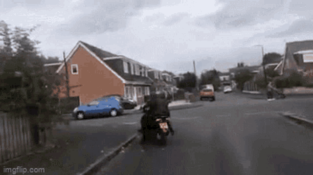 a person riding a motorcycle down a residential street with a license plate that says lkc 88 on it