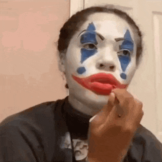 a woman is wearing a clown costume and applying lipstick to her lips .