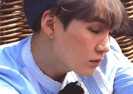 a close up of a person 's face with a blue shirt and earrings .