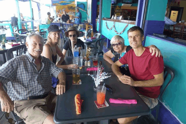 a group of people are sitting at a table with drinks in front of a coca cola sign