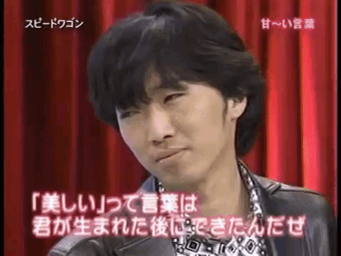a man is making a funny face in front of a red curtain with japanese writing
