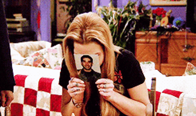 a woman is holding a picture of a man in her hair