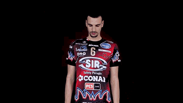 a man in a red shirt with the number 6 on it stands with his arms crossed