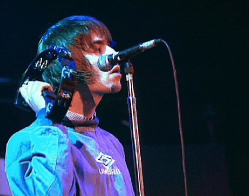 a man singing into a microphone wearing a blue jacket that says umbro