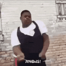 a man in a black vest is dancing in front of a brick building .