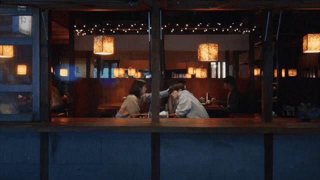 a couple sitting at a table in a restaurant looking out the window