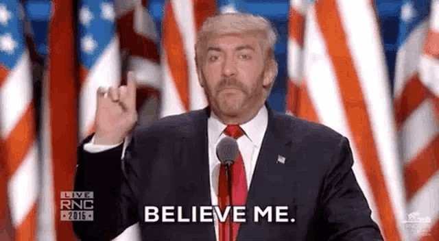 a man in a suit and tie is giving the middle finger and saying `` believe me '' while giving a speech .