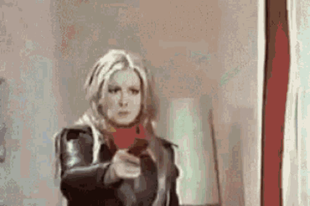 a woman is pointing a gun at the camera while standing in front of a window .