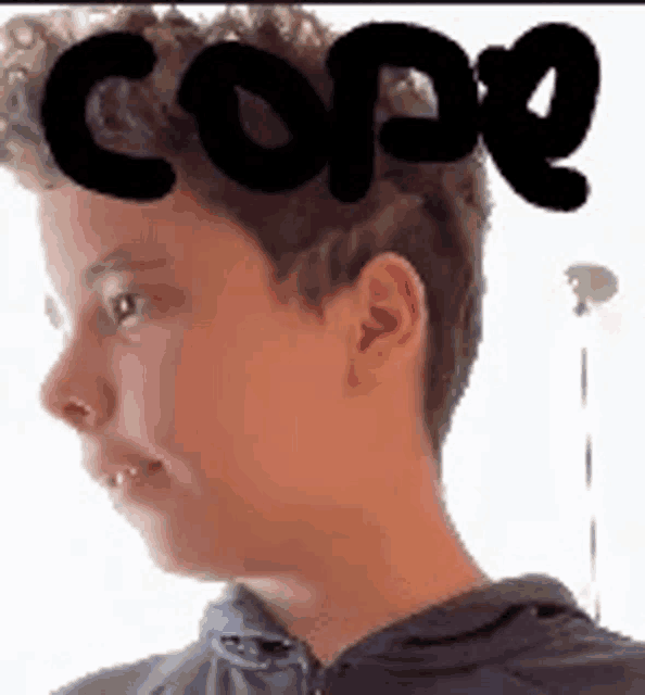 a young boy with curly hair is wearing a hoodie and has the word cope on his head .