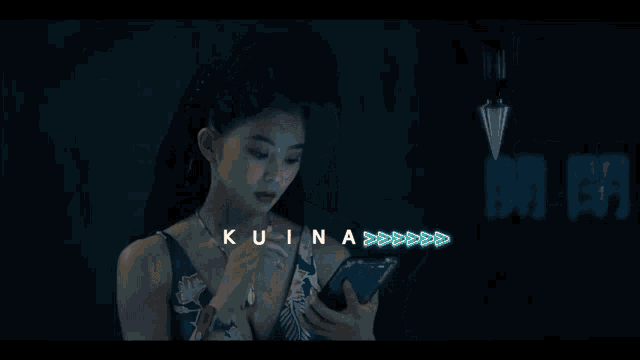 a woman looking at a cell phone with the word kuina written on the bottom