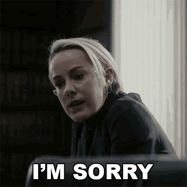 a woman says i 'm sorry while sitting in front of a window