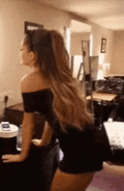 a woman in a black dress is standing in a living room