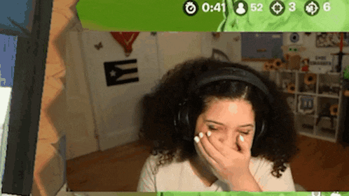 a woman wearing headphones is covering her mouth in front of a screen that shows the time of 0:41