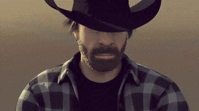 a man with a beard wearing a black cowboy hat
