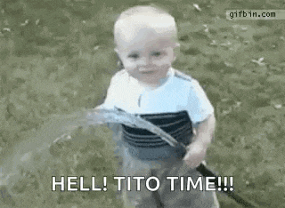 a baby is standing in the grass holding a hose and yelling .