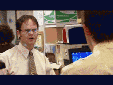 a man in a white shirt and tie talking to another man in an office