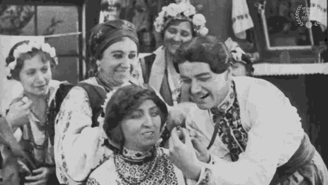 a black and white photo of a group of people with a laurel wreath in the corner