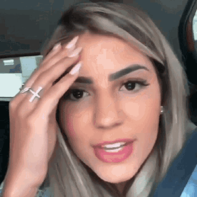 a woman with a ring on her finger is holding her head .