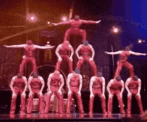 a group of people are standing on top of each other on a stage .