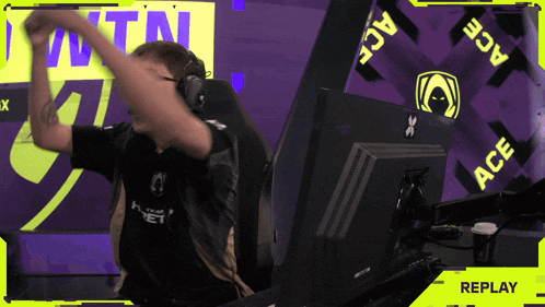 a man wearing headphones is sitting in front of a screen that says replay