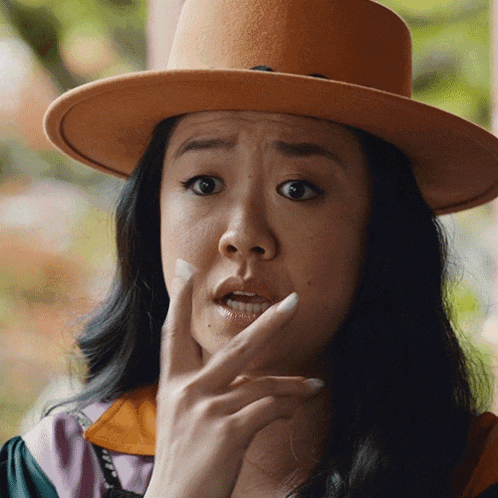 a woman wearing an orange hat covering her mouth
