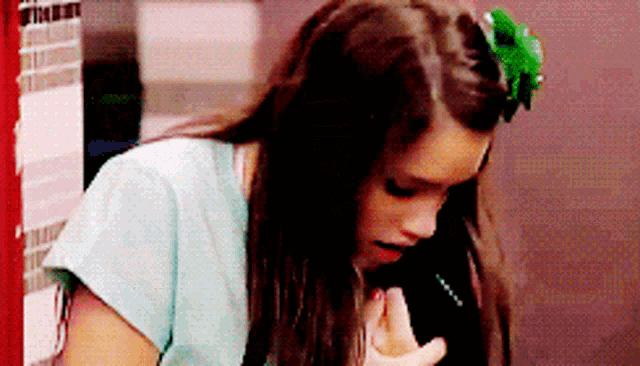 a girl with a green flower in her hair talks on a cell phone