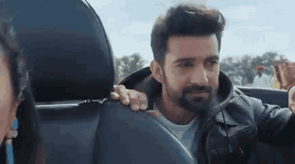 a man with a beard is sitting in a car with a woman .